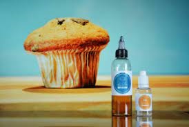 a muffin in the background and 2 e-liquid bottles